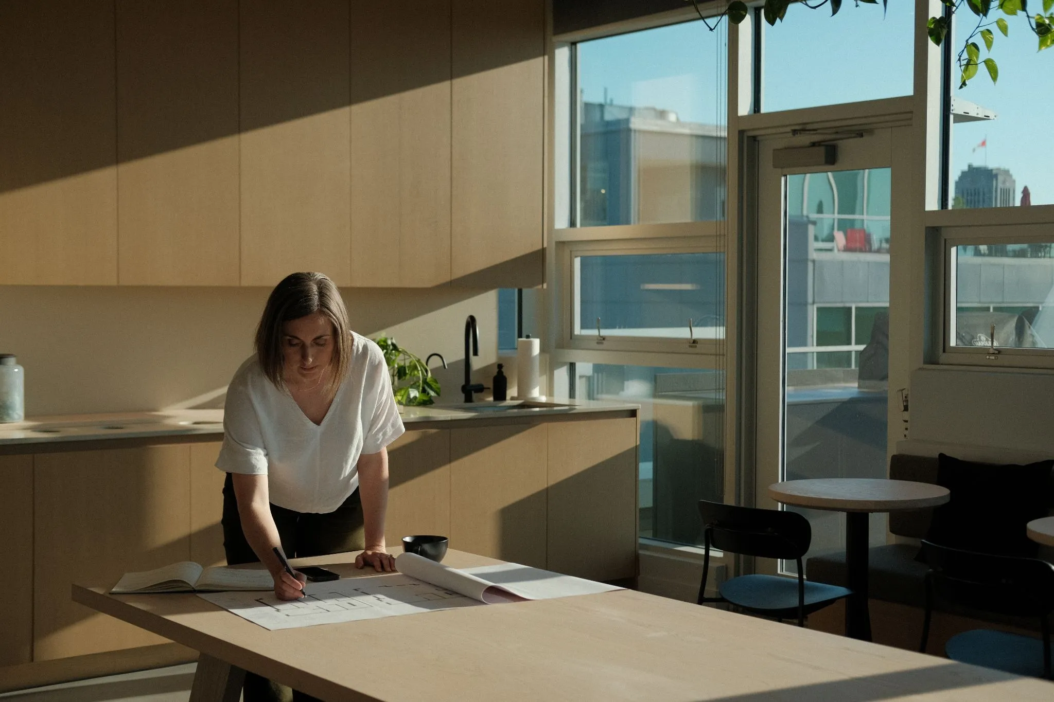 Rebecca Sorbara reviewing architectural documents at workspace with natural sunlight